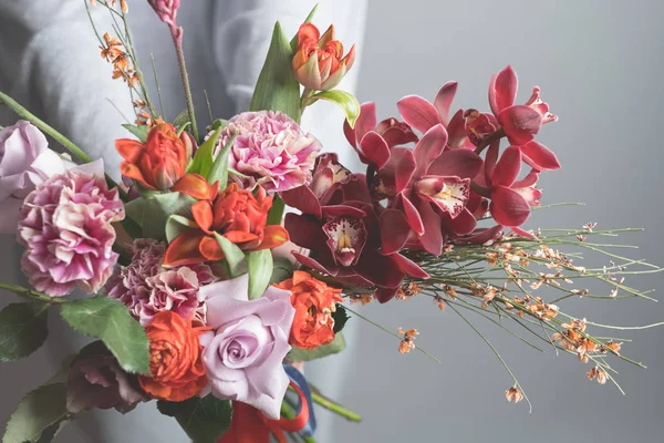 灰色の背景に美しい花の花束を持ってファッション女性 — ストック写真