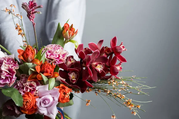 灰色の背景に美しい花の花束を持ってファッション女性 — ストック写真