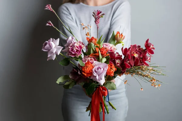 灰色の背景に美しい花の花束を持って女性のファッションの写真 — ストック写真