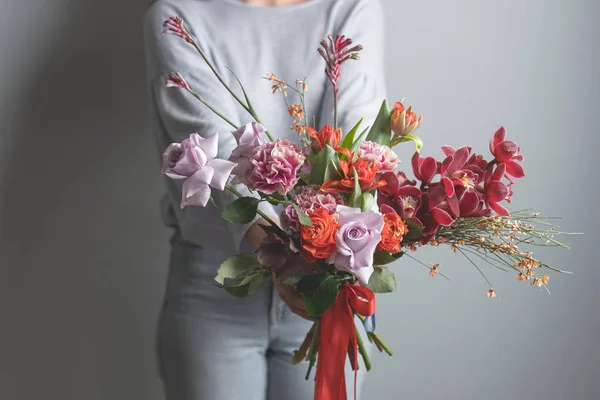 灰色の背景に美しい花の花束を持って女性のファッションの写真 — ストック写真