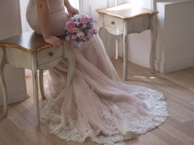 vintage masada oturan ve pastel pembe ve mor çiçekli düğün buket tutan güzel elbiseli zerafet gelinin yakın çekim fotoğraf