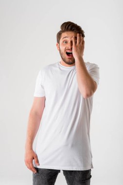 Genç azarlama portre başını tutan gri arka plan üzerinde Beyaz tişörtlü adam sakallı 