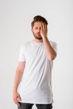 gri arka plan üzerinde Beyaz tişörtlü genç düşünceli sakallı adam portresi 
