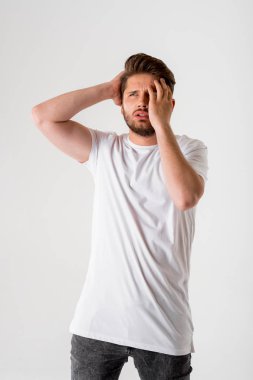 gri arka plan üzerinde Beyaz tişörtlü genç şüpheli sakallı adam portresi 