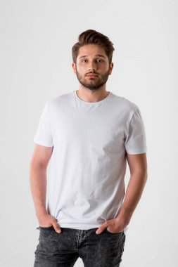 gri arka plan üzerinde Beyaz tişörtlü genç sakallı adam portresi 