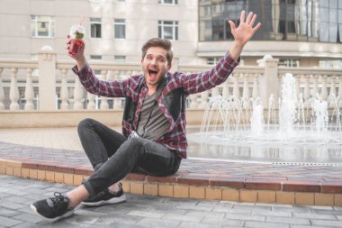 Ekose gömlek İçecek suyu açık çeşme arka plan üzerinde şehir merkezinde genç sakallı adam portresi