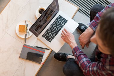laptop kapalı gri kanepe arka plan üzerinde kullanarak ekose gömlekli genç sakallı adam portresi