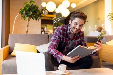 ekose gömlekli genç sakallı adam portresi gri kanepe arka plan üzerinde kapalı kitap okumak