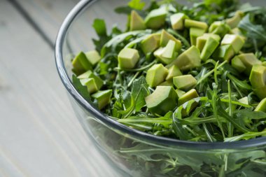 sağlıklı taze yeşil salata avokado ve ahşap masa üzerinde cam kapta roka ile yakın çekim fotoğraf 