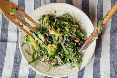 taze yeşil salata roka ve ıspanak ahşap çatal ve kaşık masada beyaz plaka ile yakın çekim fotoğraf