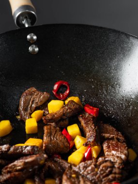 Asya fast food pirinçleri kızartılmış et ve baharatlı sebzelerle pişirilen erişteler aşçı tarafından tavada pişirildi. Yemek tarifi konseptini kapat.