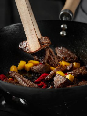 Asya fast food pirinçleri kızartılmış et ve baharatlı sebzelerle pişirilen erişteler aşçı tarafından tavada pişirildi. Yemek tarifi konseptini kapat.