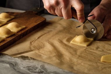 Ahşap masa arkasında elle yapılan ricotta peynirli ravioli makarnası pişiriyorum..