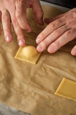 Ahşap masa arkasında elle yapılan ricotta peynirli ravioli makarnası pişiriyorum..