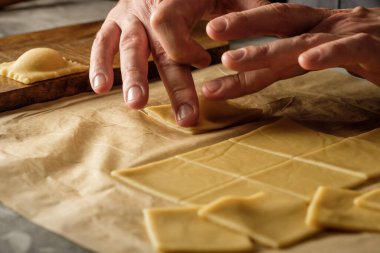 Ahşap masa arkasında elle yapılan ricotta peynirli ravioli makarnası pişiriyorum..