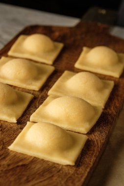 Ahşap masa arkasında elle yapılan ricotta peynirli ravioli makarnası pişiriyorum..