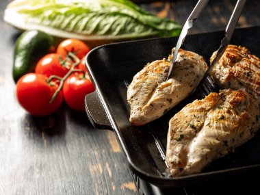 Tavuk fileto ızgarada pişiyor Şefin elleriyle siyah arka planda