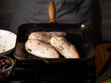 Tavuk fileto ızgarada pişiyor Şefin elleriyle siyah arka planda