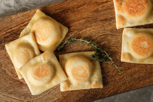 パスタラビオリは キッチンの背景にチーズパルメザンチーズとハーブ伝統的なイタリア料理のレシピとホワイトプレートで提供しています — ストック写真