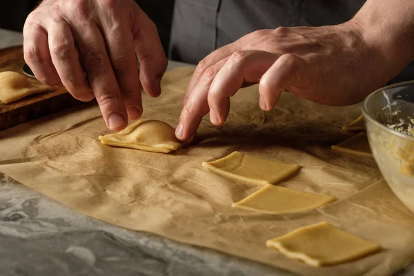 木製のテーブルの背景に調理の手でリコッタチーズ手作りのラビオリパスタを調理 — ストック写真