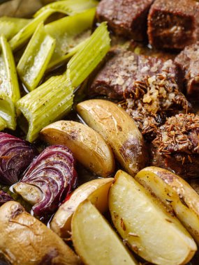 Sulu etli güveç, patates. Soğan, kereviz ve çiftlik usulü fırında kızartılmış baharatlar. Sağlıklı ev yapımı yemek tarifi. Ahşap masa arka planı. Üst görünüm, düz görünüm, genel bakış