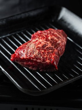 Izgarada biftek fileto pişiriyorum. Siyah arka planda tuz ve biber ve fotokopi uzay metni. Yemek tarifi konsepti