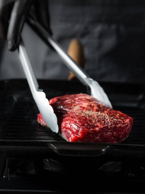 Izgarada biftek fileto pişiriyorum. Siyah arka planda tuz ve biber ve fotokopi uzay metni. Yemek tarifi konsepti