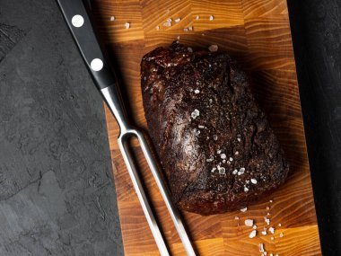 Izgara sulu biftek seçilmiş mermer et dilimler üzerinde tahta masa üzerinde siyah arka plan halk ve bıçak ile kesilmiş