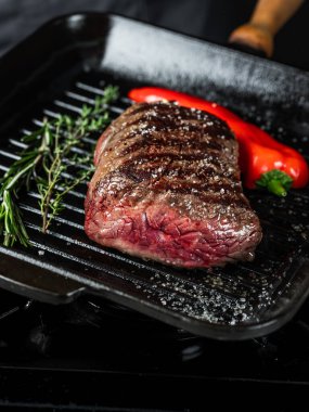 Izgarada biftek fileto pişiriyorum. Siyah arka planda tuz ve biber ve fotokopi uzay metni. Yemek tarifi konsepti