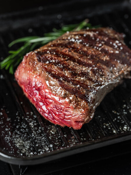 Grilled juicy beef steak selected marbled meat cutting on slices on wooden desk black background with folk and knife