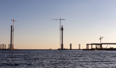 Gün batımını çerçevede nehir üzerinde köprü inşaatı.