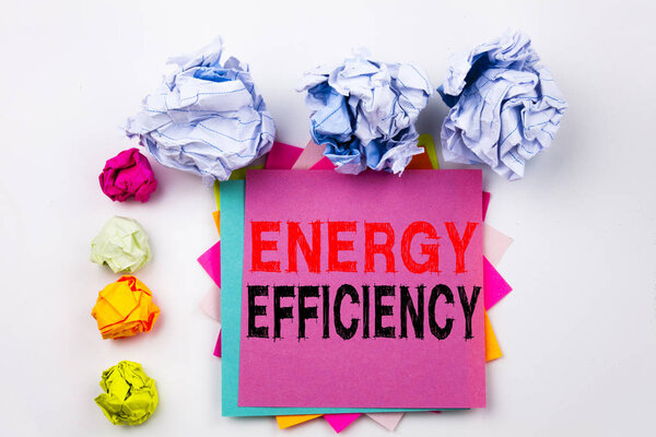 Writing text showing Energy Efficiency written on sticky note in office with screw paper balls. Business concept for Building Technology Efficiency on the white isolated background.