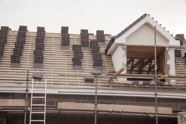Werken op het dak bekleding en steunpoten of ladder van een nieuwe, twee verhaal, commerciële flatgebouw — Stockfoto