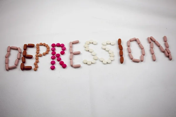 Слово депресії, написання на білому тлі на таблетках — стокове фото