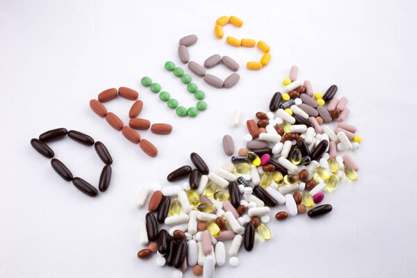 Медицинская помощь концепция здоровья, написанная с таблетками капсула препарата слово препарат на белом изолированном фоне с копировальным пространством
