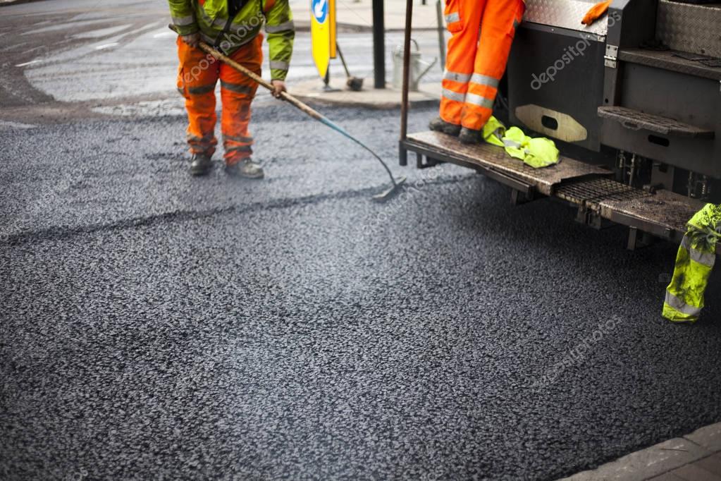A roadworks on the street new asphalt with workers, Road Roller Road Construction Machinery.