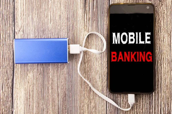 Word, writing Mobile Banking. Business concept for Internet Banking e-bank written on mobile cell phone mobile and power-bank charger on old wood wooden background