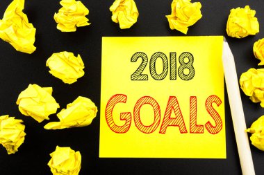 2018 hedefleri gösteren el yazısı metin. Finansal planlama, yapışkan not kağıdına siyah arka plan üzerinde yazılı iş stratejisi için yazma iş kavramı. Sarı kağıtları arka plan üzerinde katlanmış