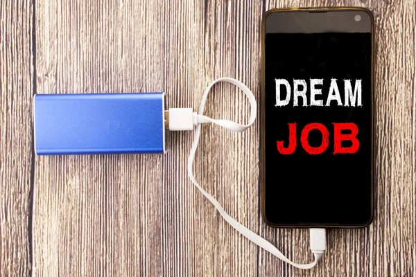 Word, writing Dream Job. Business concept for Dreaming about Employment Job Position written on mobile cell phone mobile and power-bank charger on old wood wooden background