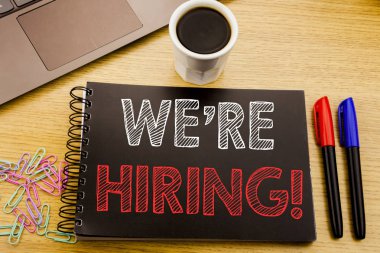 Biz çoğu işe şimdi gösteren el yazısı duyuru metin. İş kavramı için işe alım insan kaynakları defter kitap dizüstü kahve ile ofiste ahşap arka plan üzerinde yazılı