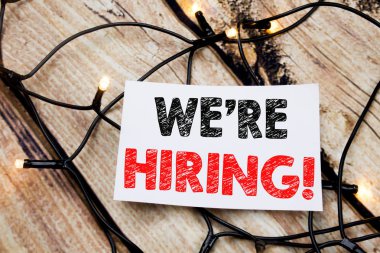 El yazısı metnini başlık biz çoğu işe şimdi gösteriyor. İş kavramı için işe alım insan kaynakları ahşap arka plan üzerinde yapışkan not kağıt üzerinde yazılı yazma.