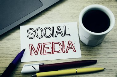 El yazısı metnini başlık sosyal medya gösterilen. Topluluk sosyal defter kitap dizüstü kahve ile ofiste ahşap arka plan üzerinde yazılı medya yazma iş kavramı