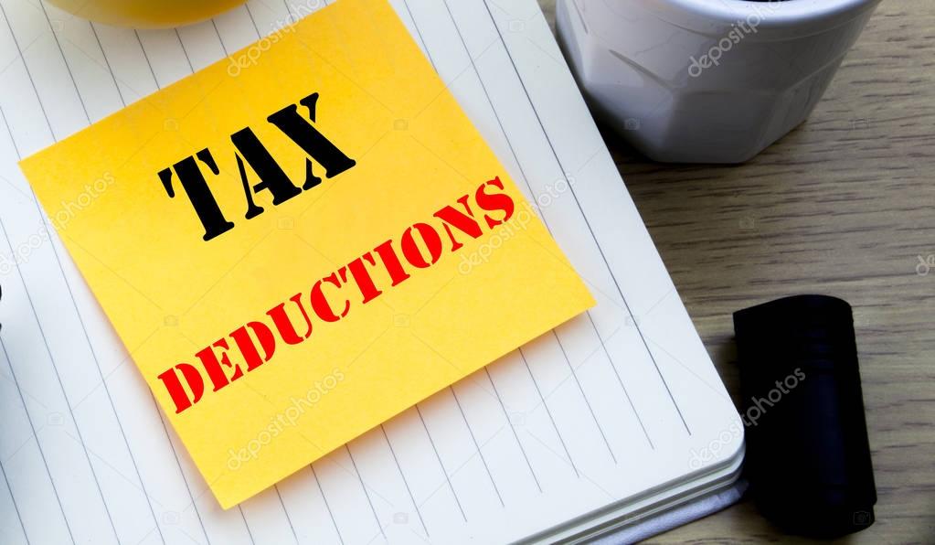 Writing text showing Tax Deductions. Business concept for Finance Incoming Tax Money Deduction written sticky note empty paper, Wooden background with copy space, Coffee and marker