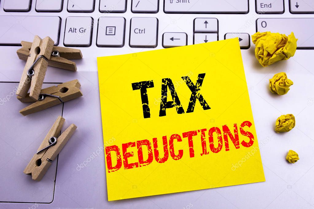 Hand writing text caption inspiration showing Tax Deductions. Business concept for Finance Incoming Tax Money Deduction written on sticky note paper on the white keyboard background.