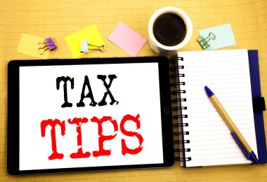 Vergi ipuçları. Vergi mükellefi yardım iade geri ödeme tablet dizüstü bilgisayarda yazılmış, yapışkan not, kahve ve kalem ile ahşap arka plan için iş kavramı