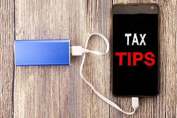Word, writing Tax Tips. Business concept for Taxpayer Assistance Refund Reimbursement written on mobile cell phone mobile and power-bank charger on old wood wooden background