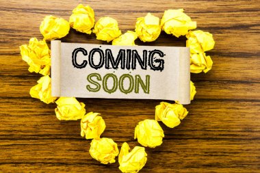 Word, Coming Soon yazma. İş kavramı koyu ahşap arka plan yapışkan not kağıdına yazılı mesaj gelecek için. Sarı katlanmış kağıt kalp anlamı sevgi ve hayranlığı ile.