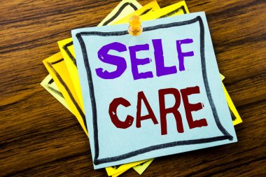 Kendine iyi bak gösterilen metin yazma. Yapışkan not kağıdına ahşap arka plan üzerinde yazılı kendi sağlık için bakım ayırdığınız için iş kavramı.