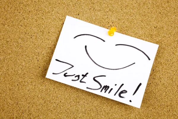 Een gele kleverige nota schrijven, bijschrift, bovenaanzicht van het opschrift van Just Smile plaknotitie geplakt in zwart ext op een kleverige nota vastgemaakt aan een prikbord kurk — Stockfoto