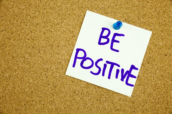 A yellow sticky note writing, caption, inscription be positive, motivational lifestyle reminders against black ext on a colorful sticky note pinned to a cork notice board — Stock Photo, Image